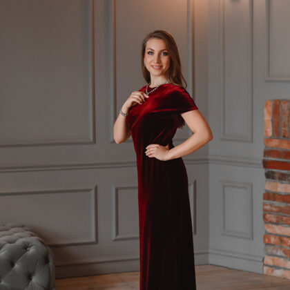 Portrait of soprano Annija Adamsone standing in a red dress